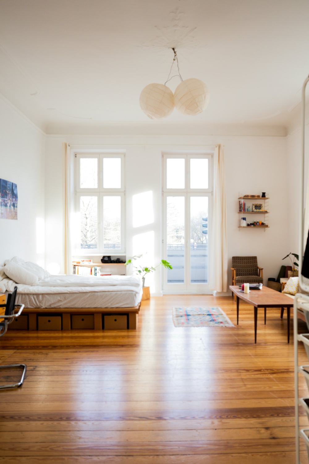 Chambre lumineuse aux murs blancs et grandes fenêtres